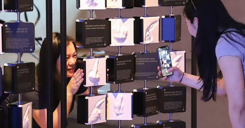 two women photograph themselves in front of the plastercast hands